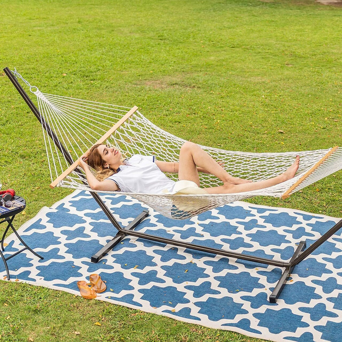 Hammock with stand and pillow, laid out on a garden lawn